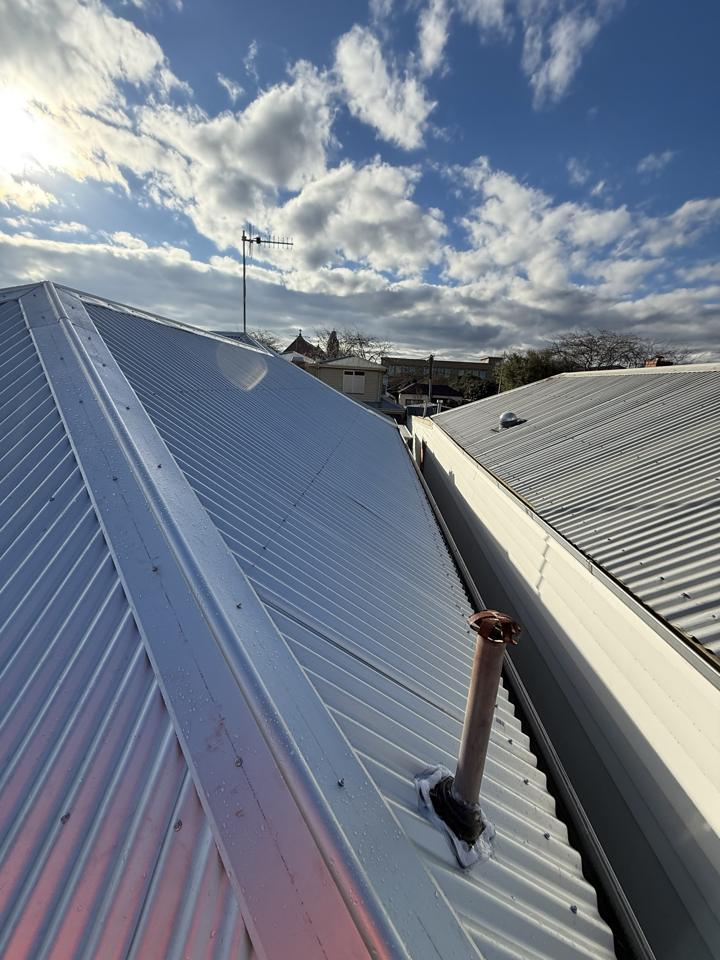 Corrugated metal roof with new ridge capping and flue flashing