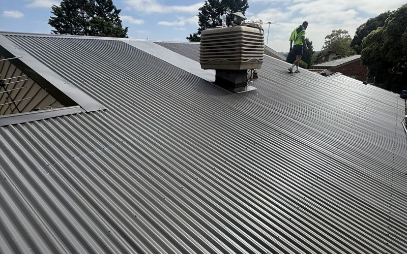 New dark Colorbond corrugated roof with a roofer finishing the job