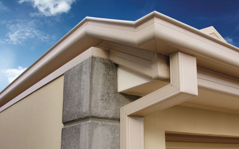 Cream gutter and square downpipe on the corner of a house
